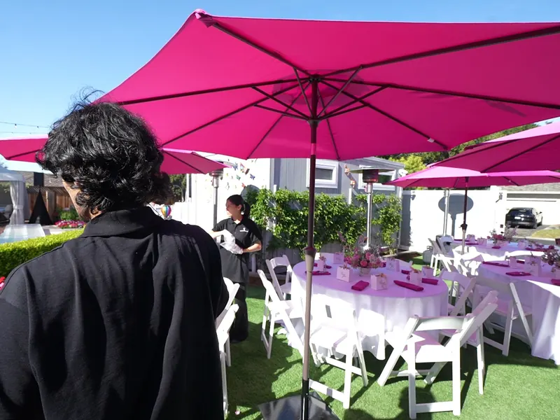 Rose-covered floral arch framing a table at an outdoor reception