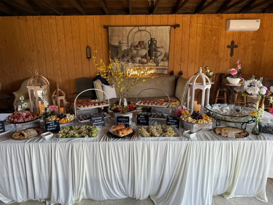 Grazing tablescape of sliced meats, tea sandwiches, fruit tarts and chilled salads pulled together with coordinated linens — grazing styling from our Concord catering florals team