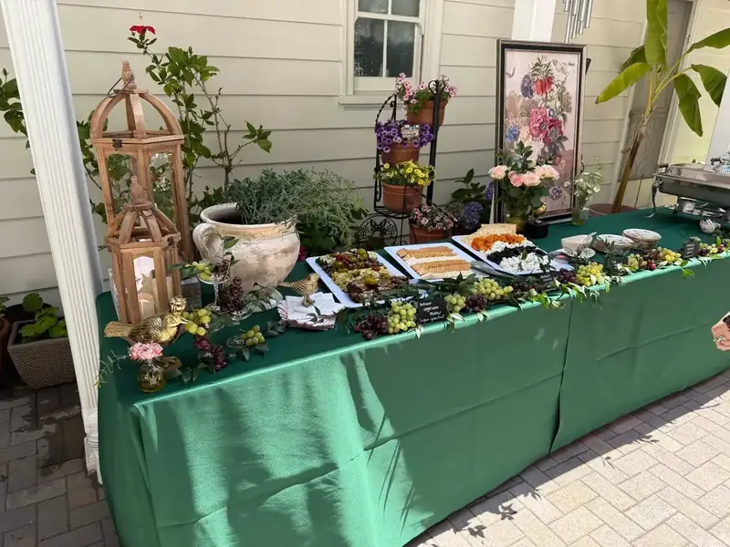 Concord private-party appetizer table by Winslow’s Catering featuring charcuterie, fruit, floral accents, and layered garden décor.